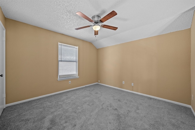 unfurnished room featuring vaulted ceiling, a textured ceiling, ceiling fan, and carpet