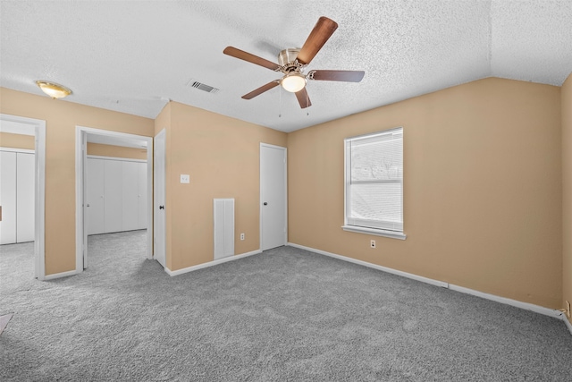 empty room with ceiling fan, light colored carpet, a textured ceiling, and vaulted ceiling