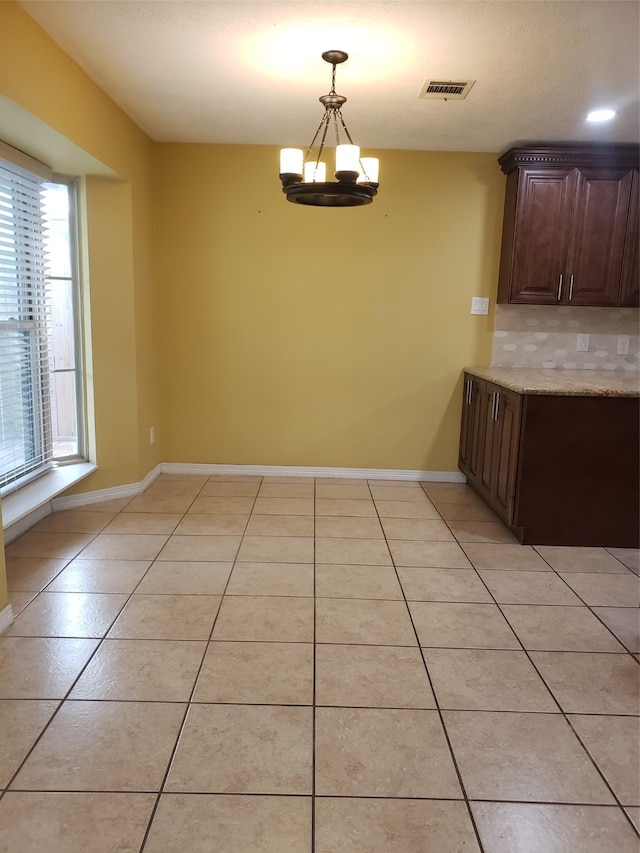 unfurnished dining area featuring light tile patterned floors and an inviting chandelier