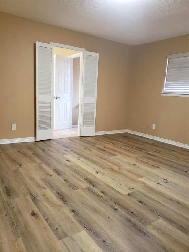 unfurnished bedroom featuring a textured ceiling and light hardwood / wood-style floors