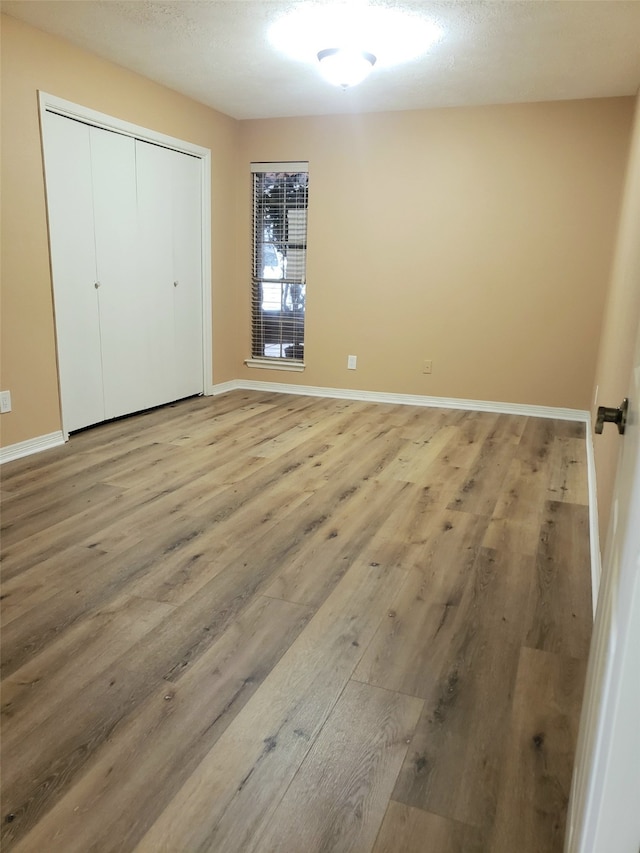 unfurnished bedroom featuring a textured ceiling, hardwood / wood-style flooring, and a closet