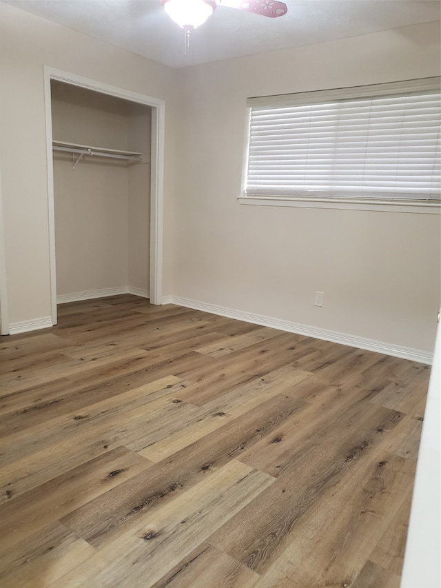 unfurnished bedroom with hardwood / wood-style floors, ceiling fan, and a closet