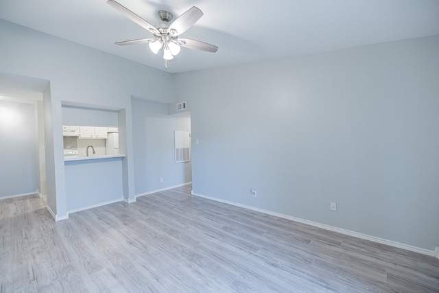 unfurnished bedroom featuring ceiling fan, sink, light wood-type flooring, and white fridge