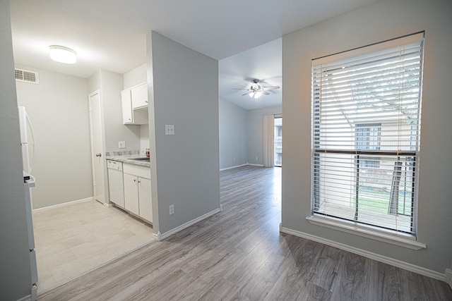 interior space with light hardwood / wood-style flooring, white cabinets, white dishwasher, and ceiling fan