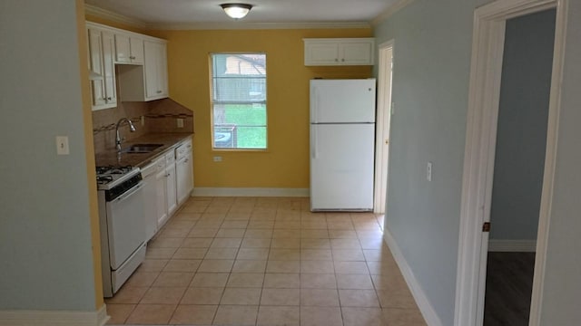 kitchen featuring white appliances, light tile patterned floors, sink, decorative backsplash, and white cabinets