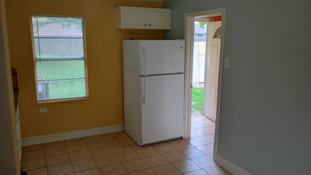 kitchen featuring light tile patterned floors, white refrigerator, and white cabinets