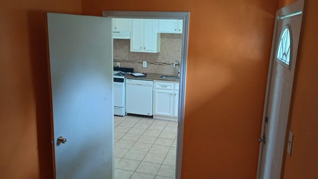 kitchen featuring white appliances, white cabinetry, sink, extractor fan, and light tile patterned flooring