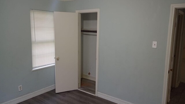 unfurnished bedroom featuring dark wood-type flooring and a closet