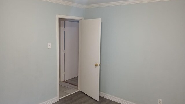 empty room featuring ornamental molding and dark wood-type flooring