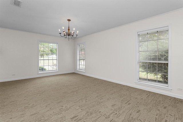 empty room featuring carpet and a notable chandelier