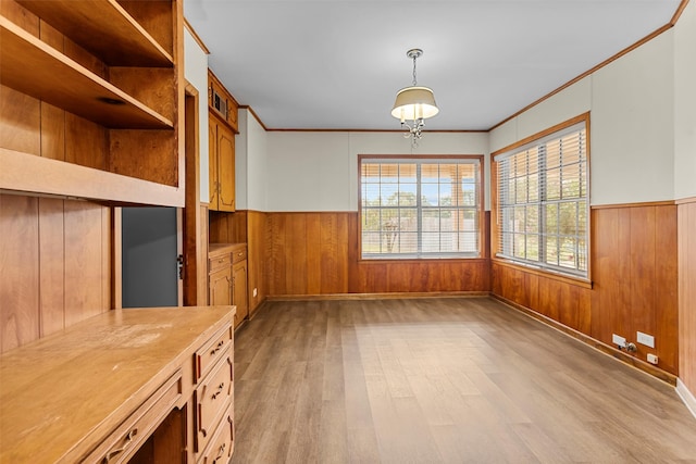 interior space with ornamental molding, wooden walls, a chandelier, and light hardwood / wood-style floors