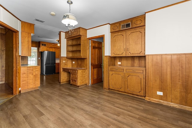 kitchen featuring wood walls, dark hardwood / wood-style flooring, hanging light fixtures, stainless steel refrigerator, and ceiling fan