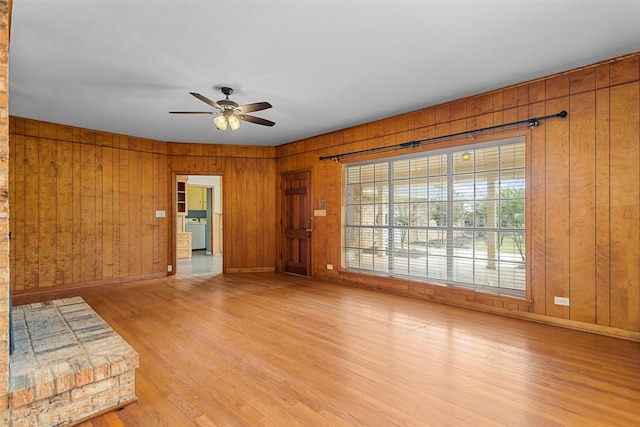 interior space with wood walls, ceiling fan, and light hardwood / wood-style flooring