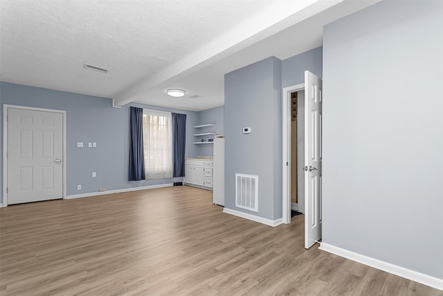 unfurnished room featuring light wood-type flooring and a textured ceiling