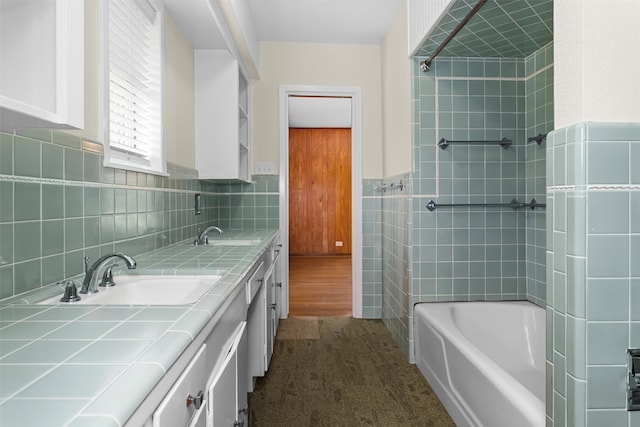 bathroom featuring vanity, wood-type flooring, tile walls, and tiled shower / bath