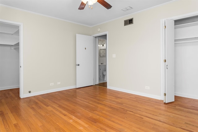 unfurnished bedroom featuring crown molding, light hardwood / wood-style flooring, ceiling fan, and a spacious closet