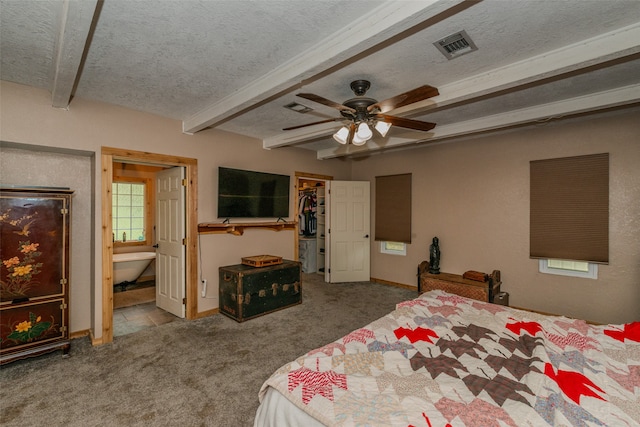 carpeted bedroom featuring a walk in closet, ceiling fan, beam ceiling, and ensuite bathroom