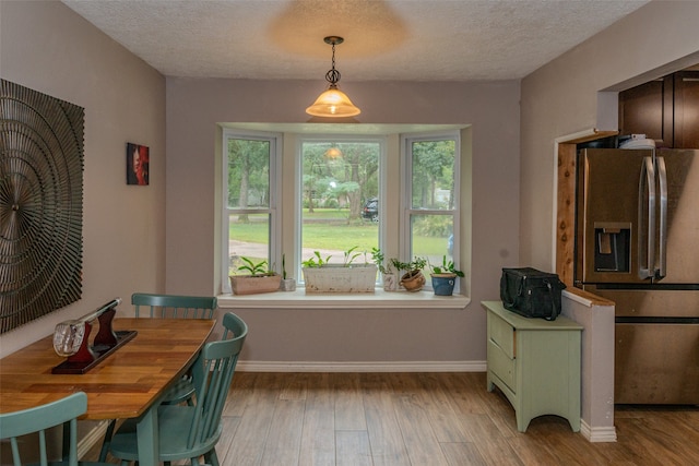 dining area featuring a textured ceiling and light hardwood / wood-style flooring