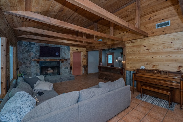 tiled living room with wooden walls, beam ceiling, wooden ceiling, and a stone fireplace