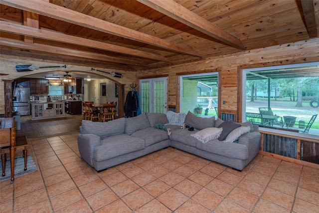 tiled living room with wood walls, wood ceiling, beamed ceiling, and ceiling fan