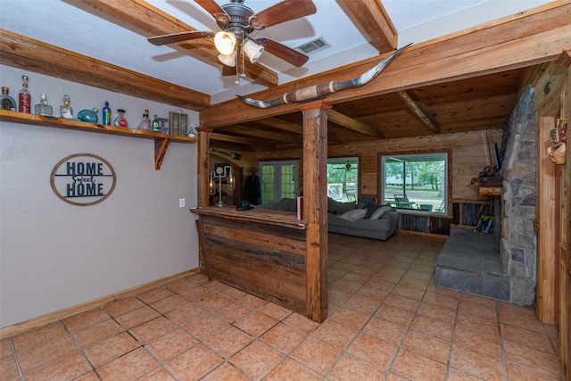 tiled bedroom with a fireplace, beam ceiling, and ceiling fan