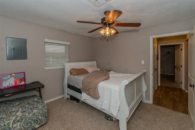 carpeted bedroom with electric panel, ceiling fan, and a textured ceiling