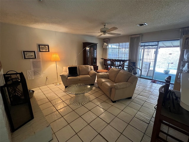 living room with ceiling fan, a textured ceiling, and light tile patterned floors