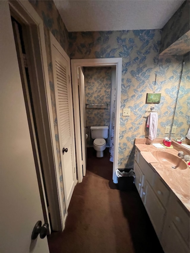 bathroom with vanity, toilet, and a textured ceiling