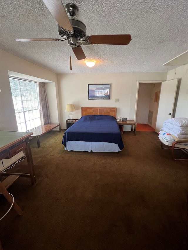 bedroom featuring ceiling fan, dark carpet, and a textured ceiling