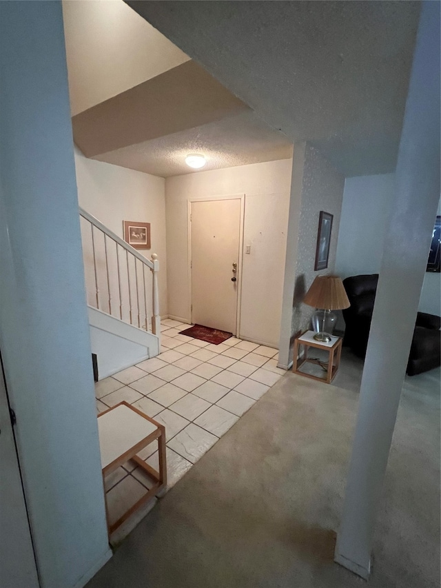 carpeted entrance foyer with a textured ceiling