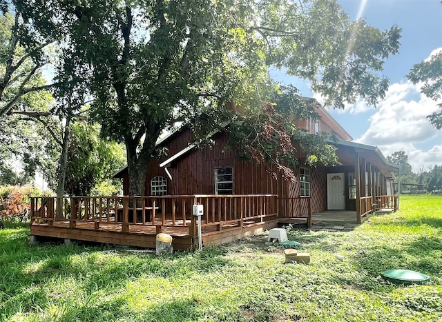 rear view of property featuring a wooden deck and a yard