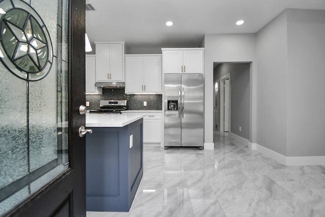 kitchen with a center island, stainless steel appliances, decorative backsplash, and white cabinets