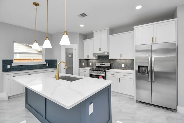 kitchen featuring decorative light fixtures, white cabinets, appliances with stainless steel finishes, and an island with sink