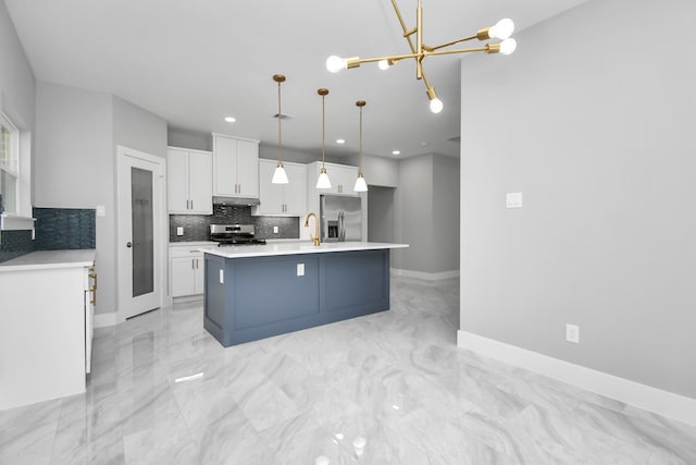 kitchen with an inviting chandelier, pendant lighting, a kitchen island with sink, stainless steel appliances, and white cabinetry