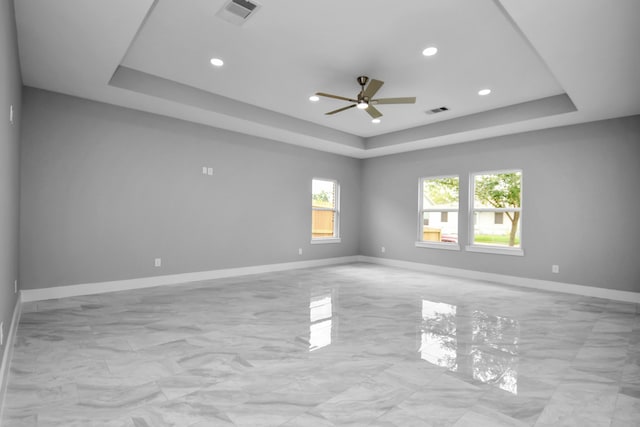 empty room featuring a tray ceiling and ceiling fan