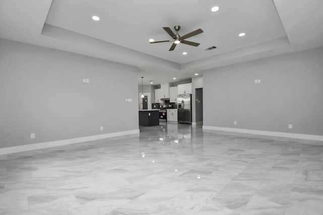 unfurnished living room with a raised ceiling and ceiling fan