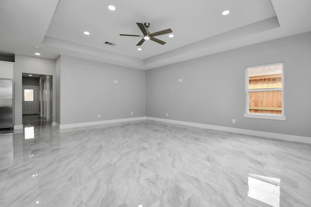 unfurnished room with ceiling fan and a tray ceiling