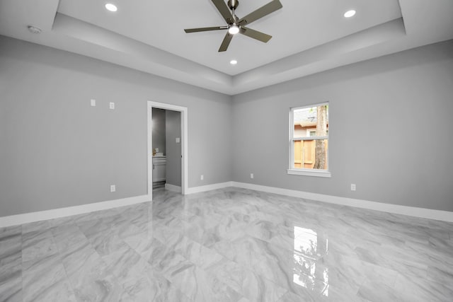 spare room featuring ceiling fan and a raised ceiling