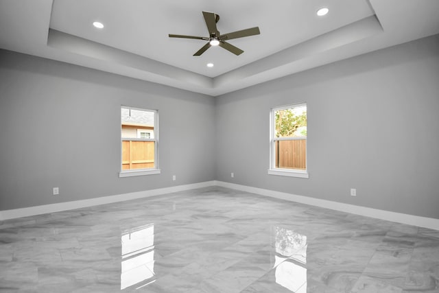 spare room featuring a raised ceiling and ceiling fan