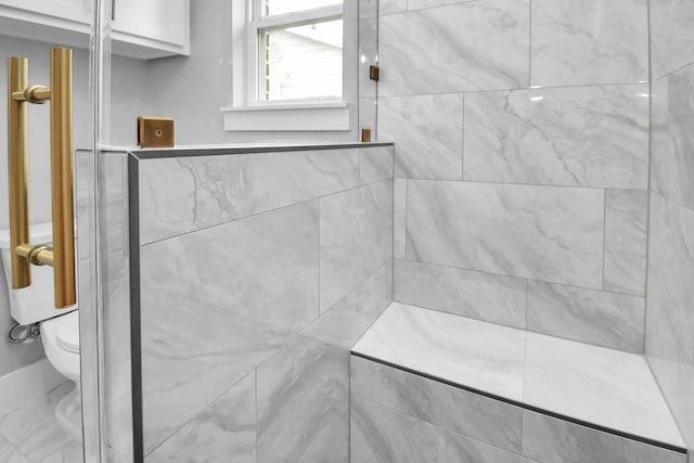 bathroom featuring tiled shower and toilet