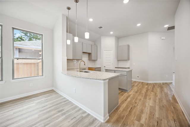 kitchen with hanging light fixtures, light hardwood / wood-style flooring, sink, gray cabinets, and kitchen peninsula