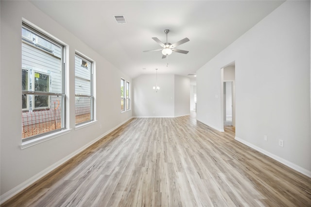 spare room with light hardwood / wood-style flooring, vaulted ceiling, and ceiling fan with notable chandelier