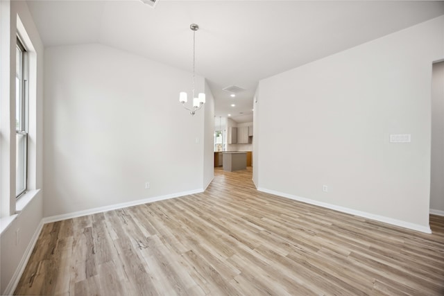 unfurnished room featuring lofted ceiling, an inviting chandelier, and light hardwood / wood-style floors