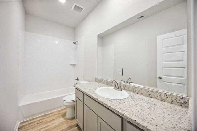 full bathroom with toilet, hardwood / wood-style flooring,  shower combination, and vanity