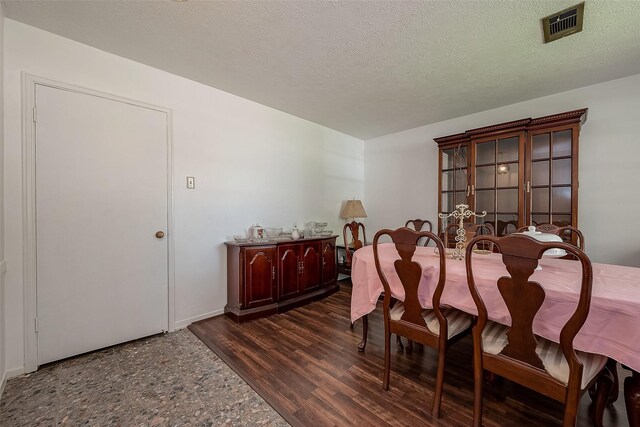 dining area with a textured ceiling and dark hardwood / wood-style floors