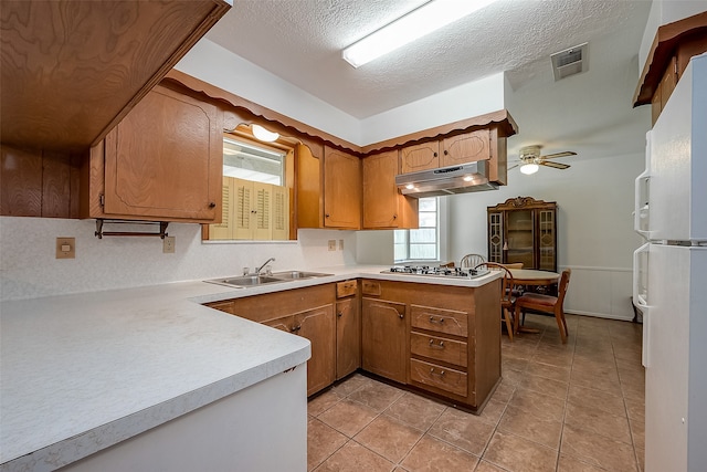 kitchen with stainless steel gas cooktop, kitchen peninsula, sink, ceiling fan, and white refrigerator