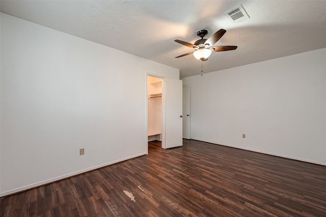 unfurnished bedroom featuring dark wood-type flooring, a closet, ceiling fan, and a spacious closet