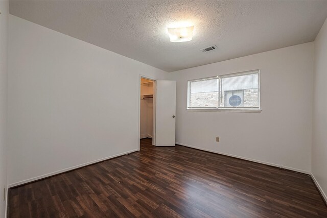 empty room with dark hardwood / wood-style flooring and a textured ceiling