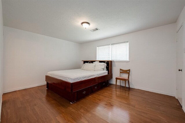 bedroom with a textured ceiling and wood-type flooring