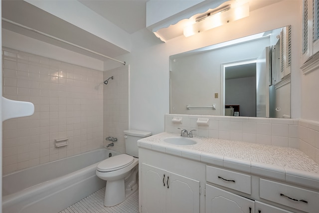 full bathroom featuring toilet, tile patterned flooring, tiled shower / bath, vanity, and tasteful backsplash